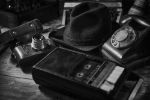 Picture of Old vintage cinematic noir scene, detective's desk with a hat, telephone, camera, portable cassette recorder, and whisky